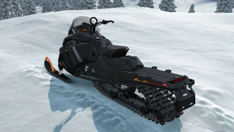Снегоход Ski-Doo Tundra LE чёрного цвета на снежном склоне у ельника, вид сзади сбоку