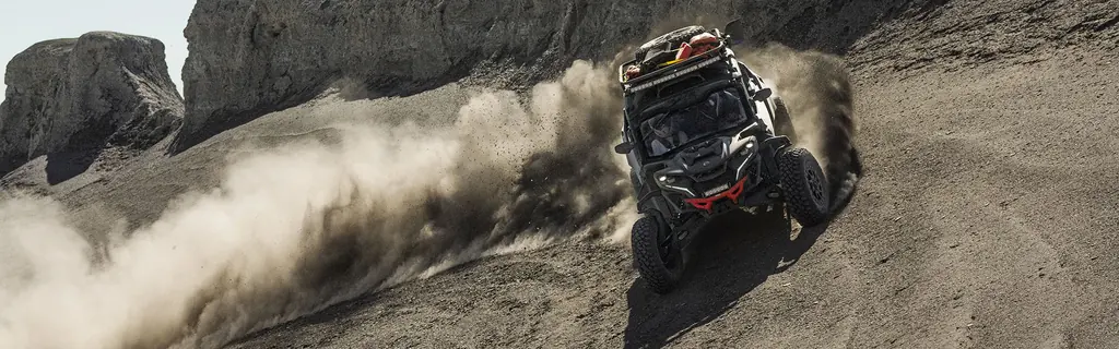 Багги Can-Am Maverick R MAX поднимает пыль на склоне у скал